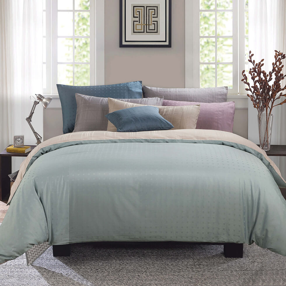 bed with green blanket in between two windows