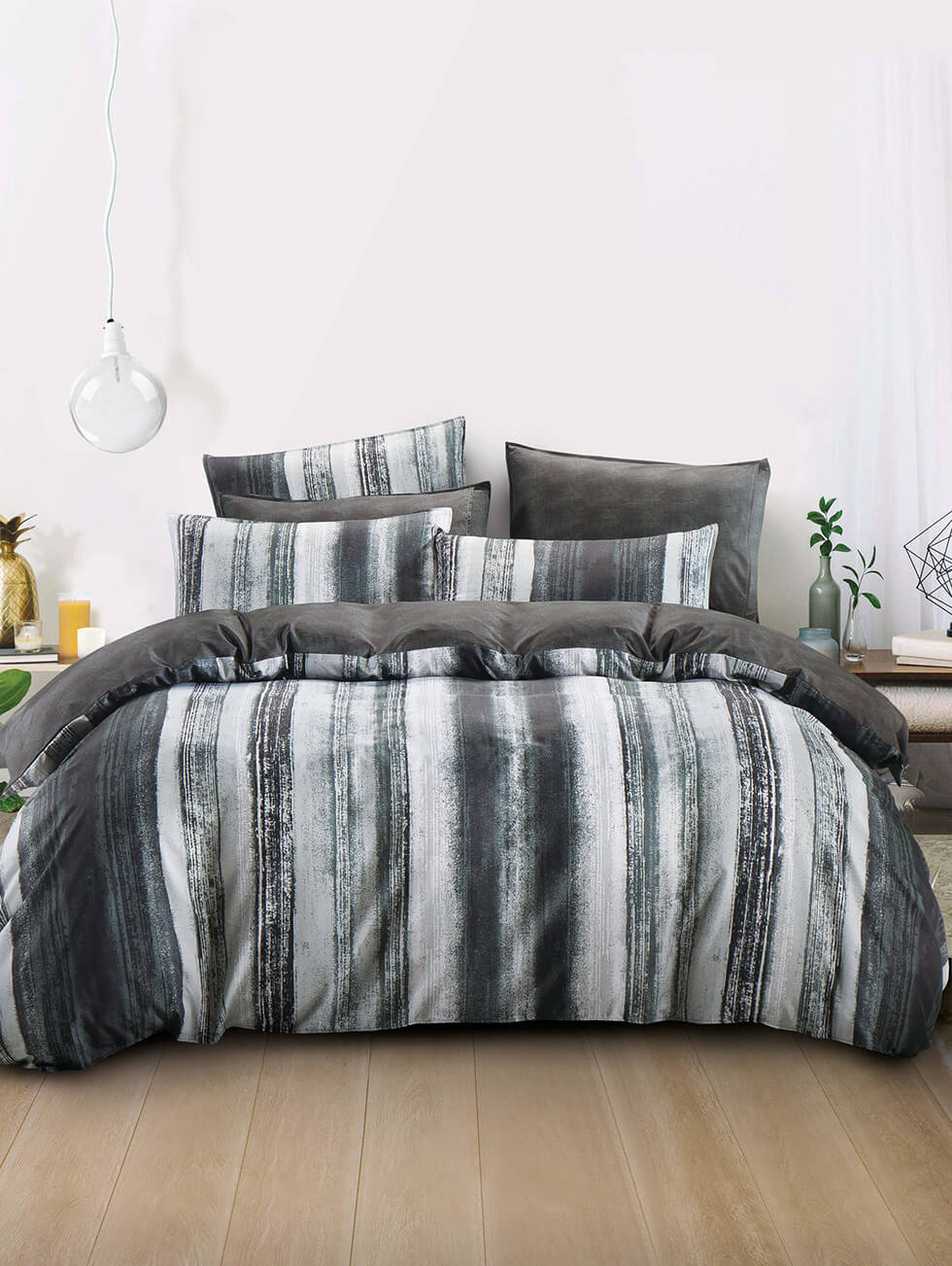 Hooga light grey and dark grey strips bed in a minimalistic room with a big hanging light bulb at the side