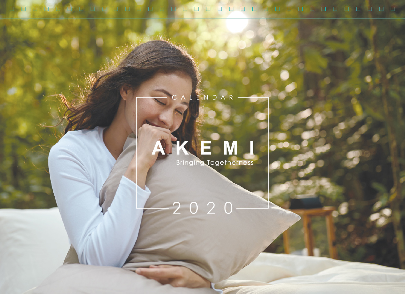 Akemi 2020 calendar with woman smiling on a bed hugging the pillow