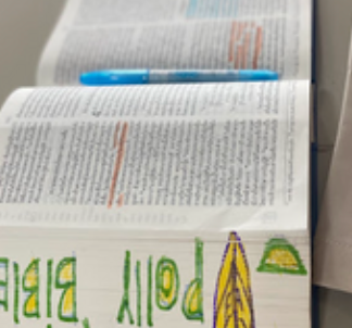 An open Bible resting on a table with the name 'Polly' colorfully drawn on the edge, symbolizing personal connection and spiritual growth during the Shear Love program.
