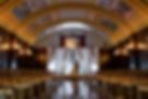 A newlywed couple at the center of the ballroom, lit up for their wedding ceremony in the Florentine Ballroom at The Congress Plaza Hotel.
