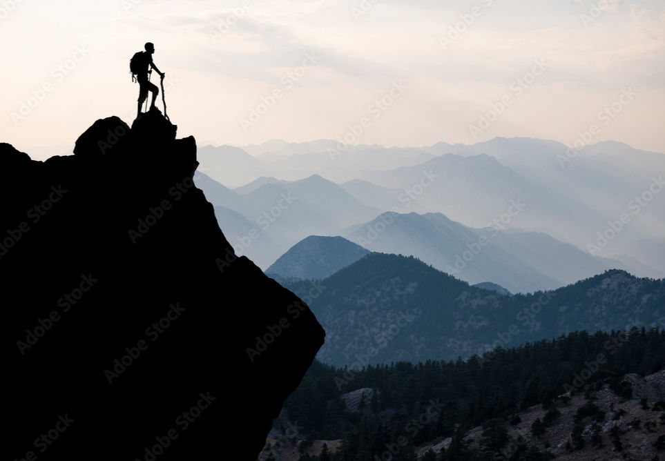 A person standing on top of a mountain, surveying their beautiful view of the horizon.