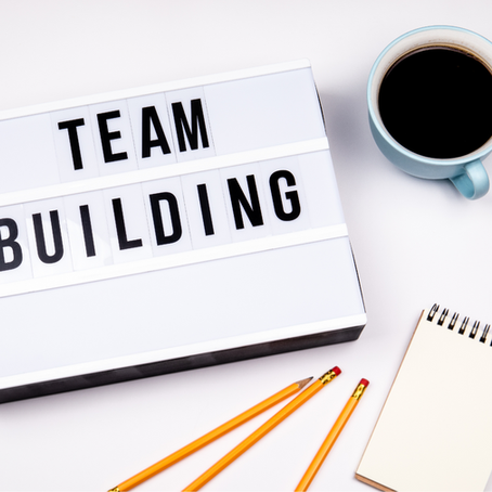 Team building concept with a lightbox sign reading “Team Building” on a desk with coffee, pencils, and a notebook, representing collaboration and workplace teamwork.