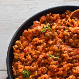 Bowl of lentil Bolognese topped with fresh basil and herbs.