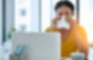 Image of woman at laptop sneezing into tissue