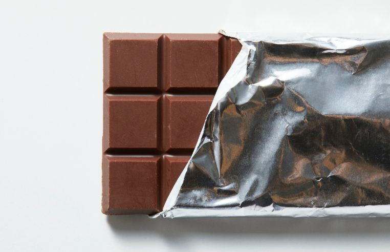 A bar of dark chocolate partly unwrapped from its foil packaging