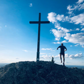 Ein Läufer beim Gipfelkreuz - Warum Trainingsplanung wichtig ist damit auch du dein Ziel erreichst.