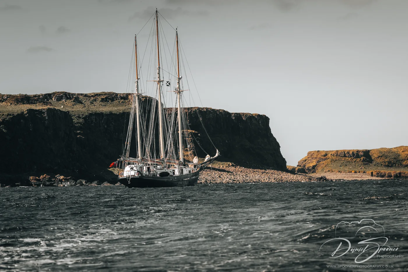 Tall-mast sailing ship off the volcanic cliffs of Lunga Island.