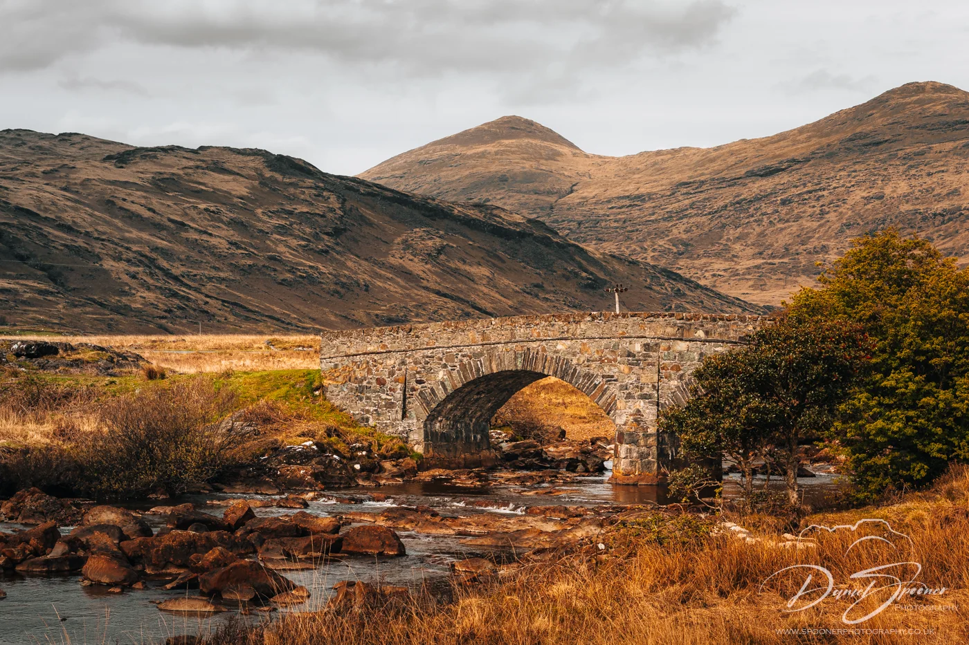 Stone bridge over stream near Loch Beg bathed in evening light.