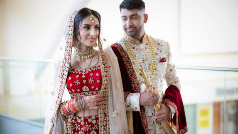 Couple in traditional wedding attire, smiling together, posing for a photo. Indian wedding.