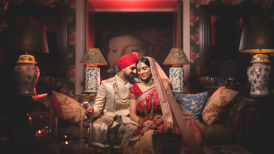 Couple in wedding attire, sitting together at the Sabyasachi suite.
