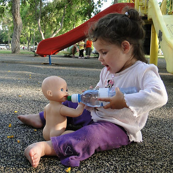 a toddler feeding her doll