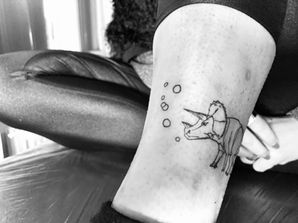 verspieltes Dino-Tattoo mit Luftblasen auf Bein