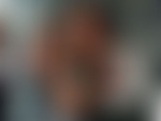 Cinematic photography of an emotional reunion in a modern international airport. A Venezuelan grandmother (60s) tearfully embraces her granddaughter (6) who holds a burgundy passport and an apostilled birth certificate. Behind them, a VTI representative in a wine-red blazer holds a professional welcome sign next to an international flight board. Large glass windows show the tarmac at sunset. VTI logo integrated on a white background in the bottom right corner.