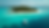 High angle view of a boat approaching a small island with turquoise water