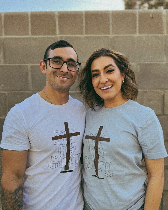 Married couple proudly showcasing their new T-shirt business, featuring custom-designed apparel with unique prints and styles
