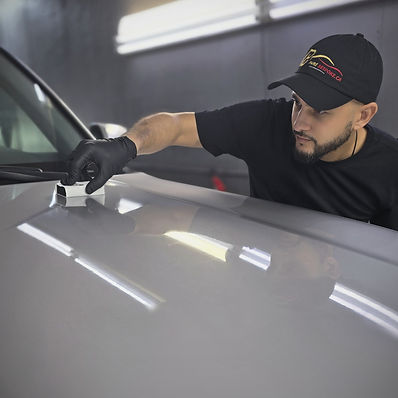 Pure Bespoke technician applying ceramic coating to a car’s hood using an applicator pad, creating a smooth, glossy surface for long-lasting shine and protection.
