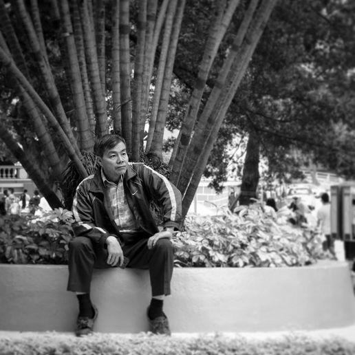 Man seated on a concrete border, looking thoughtfully. Featuring Jeff Bana Photography.