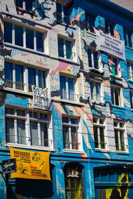 Colorful building with "Refugees" banner, text, and vibrant street art Amsterdam.