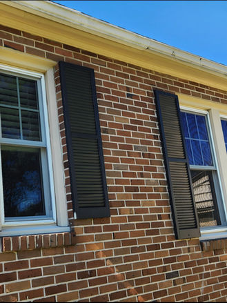 Restored exterior window shutters after sanding and repainting, providing a clean and refreshed appearance for the brick home facade.