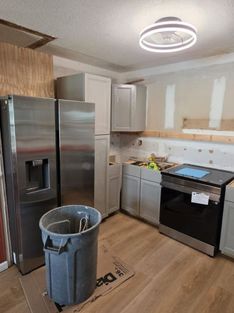 Kitchen remodel in progress with new gray cabinets, flooring, and appliance installation underway.