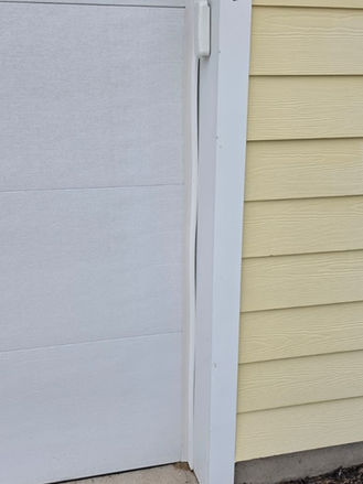 Garage door trim damage before repair, showing separated exterior trim board next to garage opening.