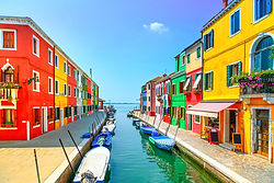 Burano island canal, lonely cloud, colorful houses and boats, Venice, Italy.
