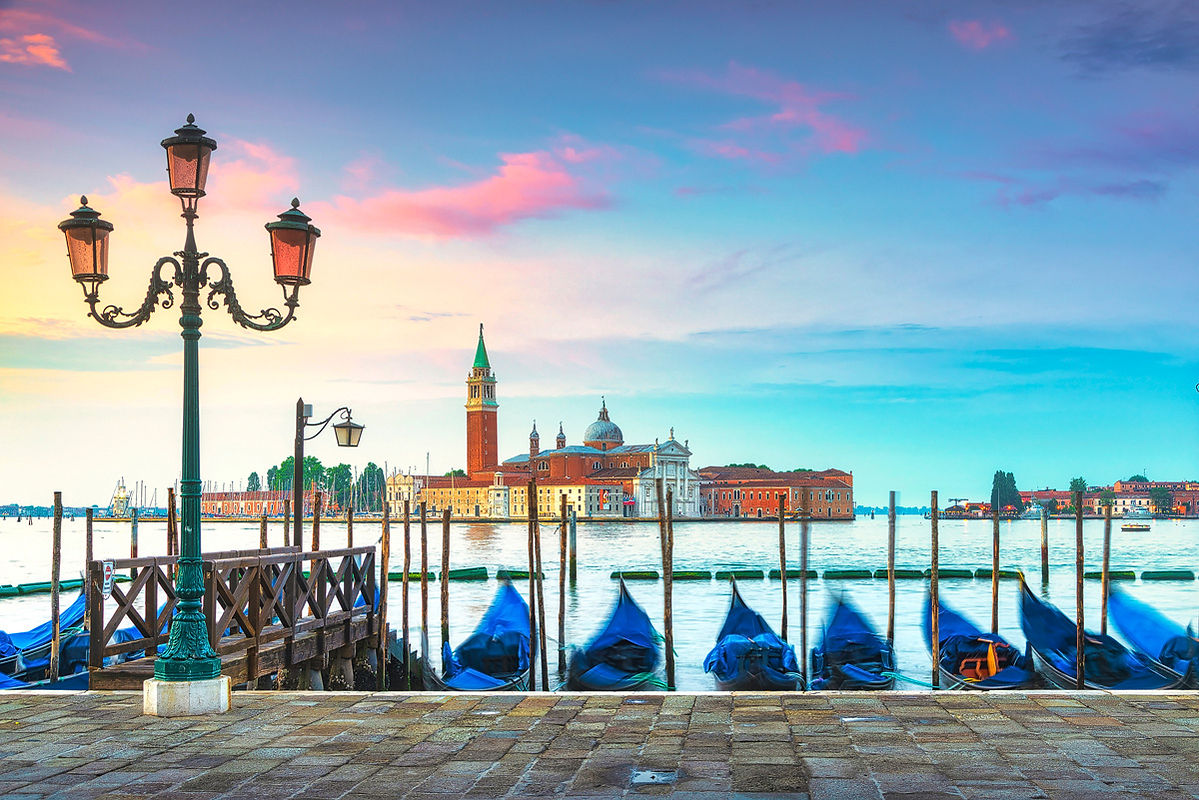 Venice lagoon at sunrise, San Giorgio Maggiore, gondolas and poles. Italy, Europe.