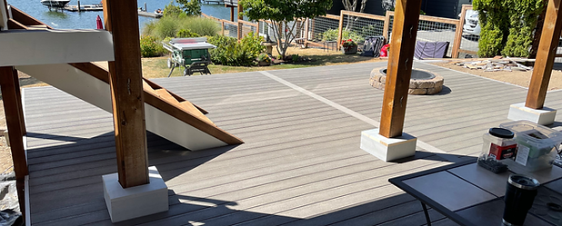 Ground-level custom deck and stairs built beneath an existing second-floor deck with Fiberon PVC decking, fire pit, and lakefront view of Lake Whatcom in Bellingham WA