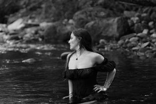 Portrait artistique de Kelly en robe noire dans un ruisseau du Pays Basque, ambiance mystique et naturelle.