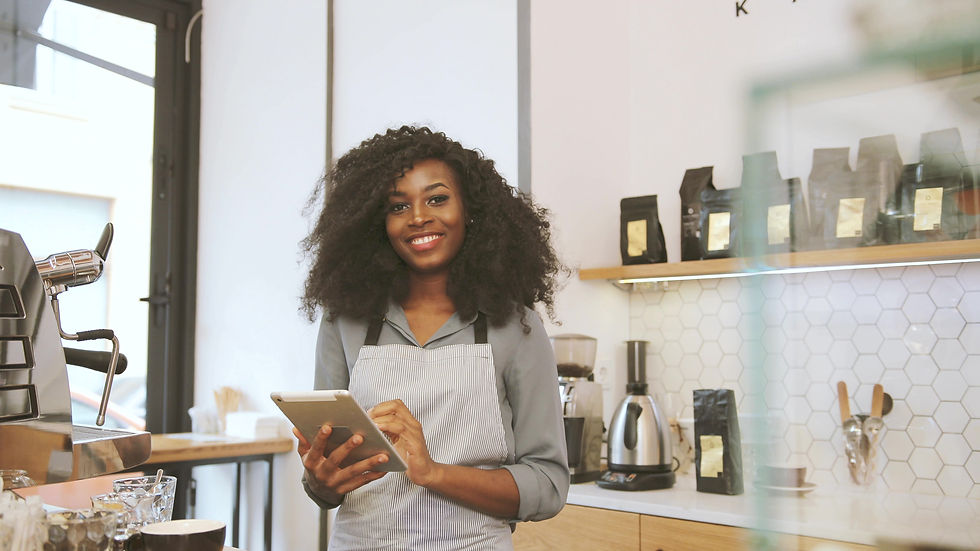 Portrait of female african barista with brown curly hair using the tablet, looking to the