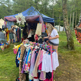 Rails of colourful clothing on display at a Second Life outdoor festival stall