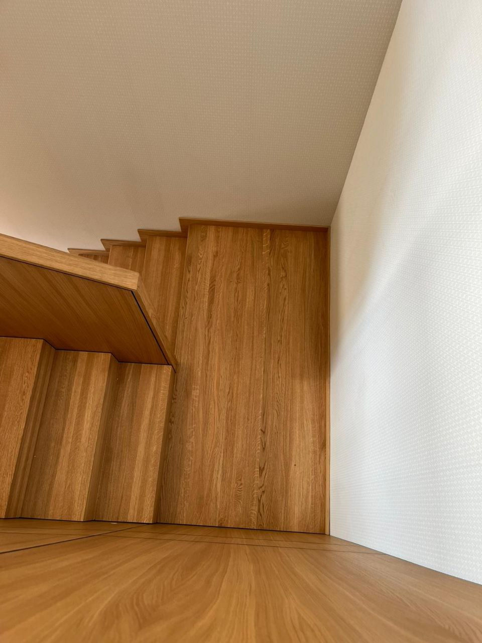Vaade tammepuidust trepile ülalt, astmed joondatud seinapaneelide joontega