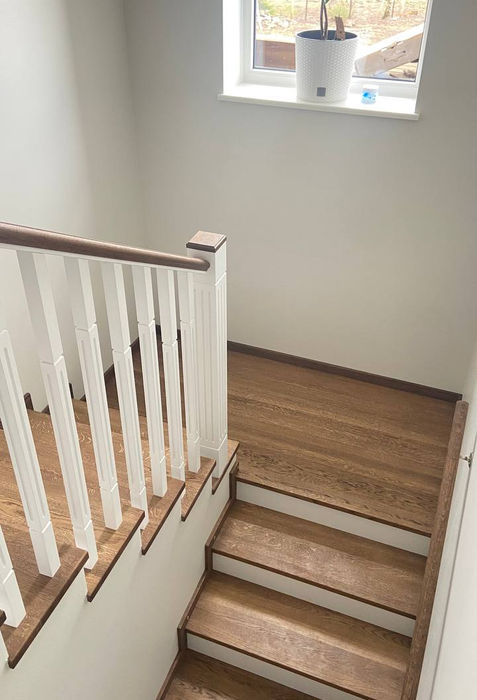 Valge ja puittrepi astmed valge seina taustal, akna all on taim valges potis.