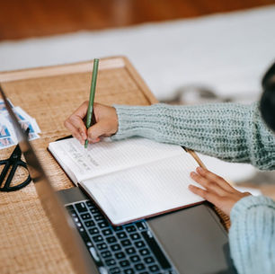 lady-writing-information-in-notepad-near-netbook