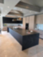Finished residential kitchen renovation with custom cabinetry, dark stone island and pendant light