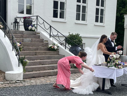 bryllupsplanlægger hjælper bruden med kjolen