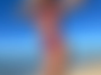 “Model wearing a wine-colored Watababe bikini by the ocean under clear blue skies.”