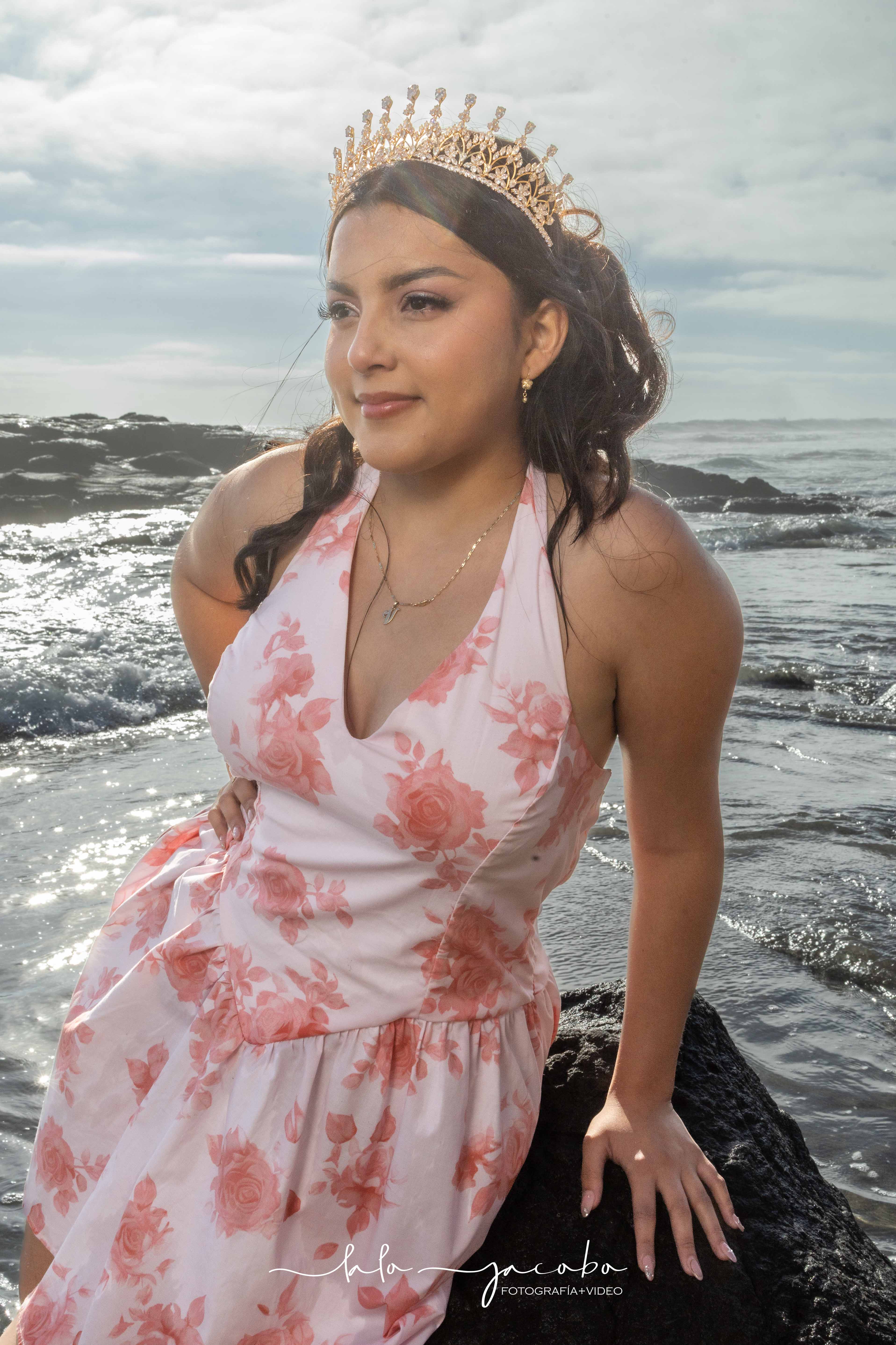 Retrato cercano de quinceañera con corona frente al mar
