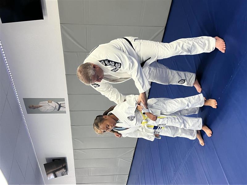Instructor helping children learn a jiu-jitsu technique