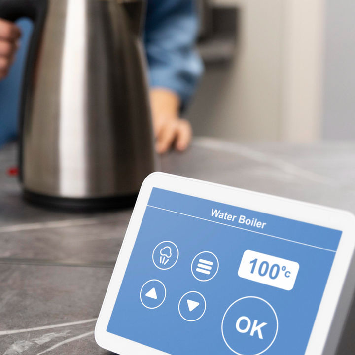 Smart home water boiler control panel on kitchen counter with person holding electric kettle.