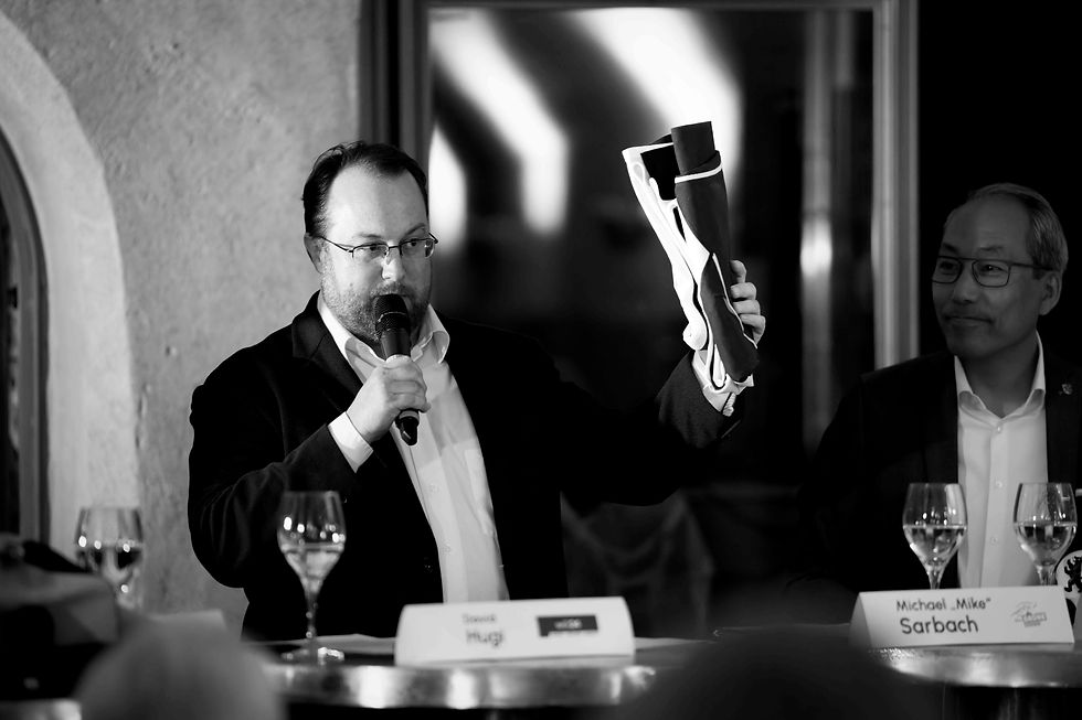 Michael Sarbach zeigt am Podium eine Wiler Fahne, die er als Hochzeitsgeschenk erhalten hat – eine echte Fahne aus dem Hause Heimgartner.