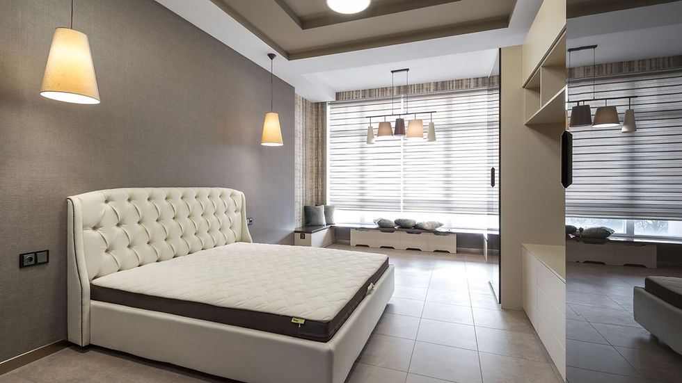 Bare white mattress on a bed frame against a grey wall in a bright Toronto bedroom before cleaning