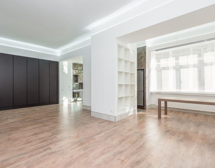 Sunlight streaming through large clean windows into a bright minimalist living room with hardwood flooring
