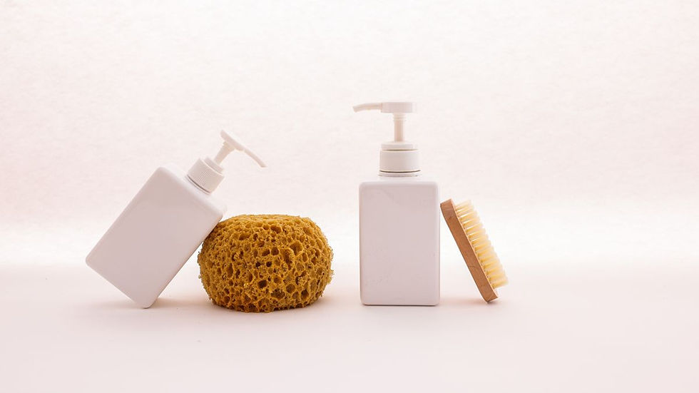 Cleaning brush, sponge and white pump bottles set out for a neutral pH tile and grout cleaning routine