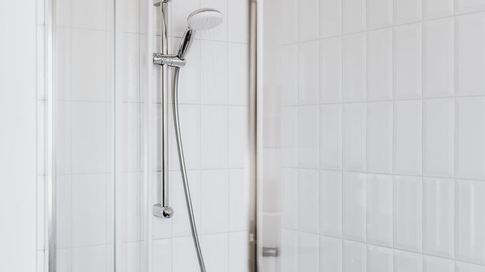 Tiled shower with chrome fixtures and clean white tiles in a bright bathroom, the surface that tile and grout cleaning protects