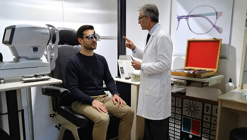Esame della vista in negozio di ottica a Ferrara: ottico controlla la vista di un cliente uomo con strumentazione professionale