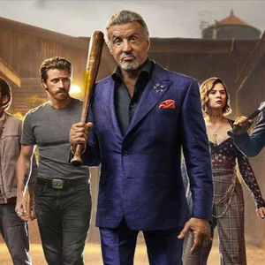 A moodily lit group of characters from Tulsa King led by Sylvester Stallone, who wields a baseball bat. 