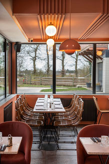 Restaurant moderne, table dressée près de grandes fenêtres donnant sur un jardin