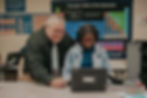 A teacher stands next to a female Aurum Prep student working side-by-side with a laptop computer.